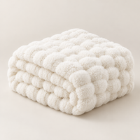 Cream white plush blanket folded in a thick stack showing its bubble texture on a light background 16