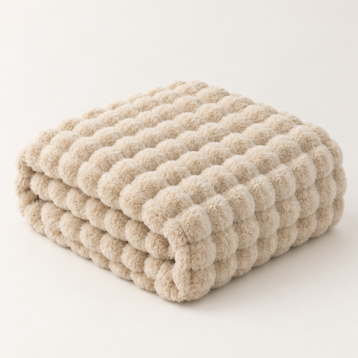Beige bubble-textured plush blanket folded in a neat stack on a plain light background 13