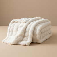 Cream white fluffy blanket folded in a neat stack with one edge hanging down 16