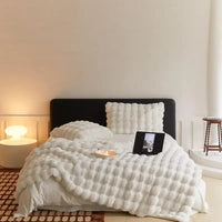 Bed styled with a white fluffy bubble-textured throw and matching cushions in a bright bedroom 7