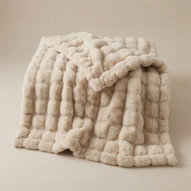 Beige faux fur blanket with raised bubble texture, loosely folded and photographed against a plain neutral background 13