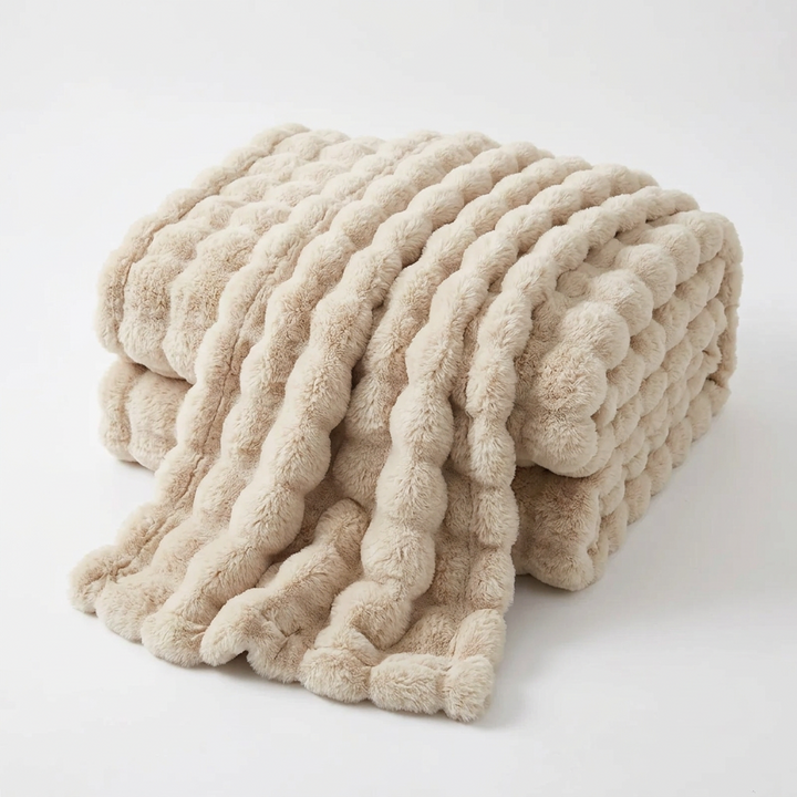 Beige bubble-textured throw folded and draped on a plain white background 16