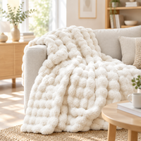 Cream fluffy bubble-textured plush blanket draped over a sofa on a woven rug in a bright living room 15