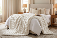 Cream bubble-textured faux fur throw draped over the foot of a made bed in a bedroom 1