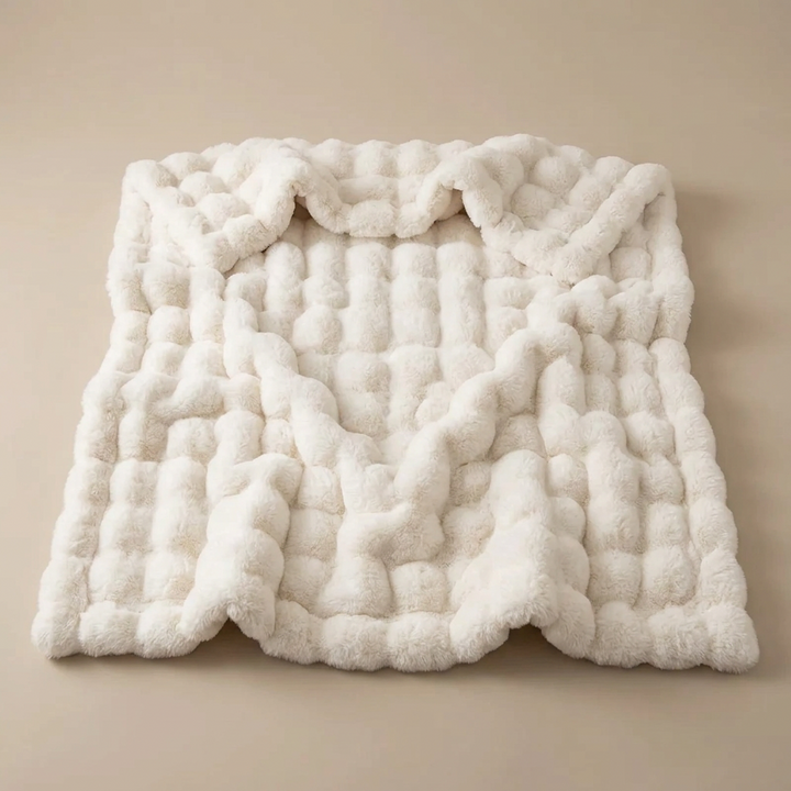 Cream white bubble-textured blanket laid flat with softly rippled folds on a plain beige background 16
