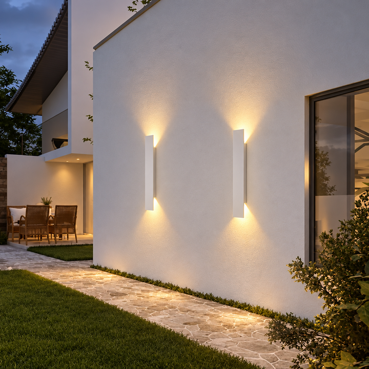 Two white wall lights on a rendered garden wall at dusk, lighting a stone path 6