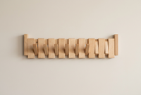 Light natural wood rack front view with several hooks folded down against a cream wall 13