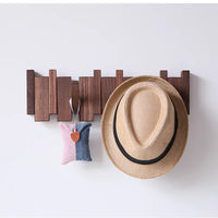 Dark wooden rack with a straw hat and a small pink and blue pouch hanging from it 4