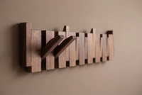 Dark wooden rack on a taupe wall with two hooks folded out and the rest flat 12