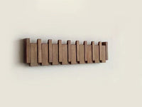 Dark walnut-toned rack mounted on a cream wall with all hooks folded flat 9